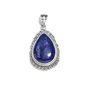 May include: A silver pendant with a deep blue lapis lazuli stone. The stone is teardrop-shaped and has gold flecks. It's set in an ornate silver frame. The pendant has a loop at the top for a chain, showcasing a classic design.
