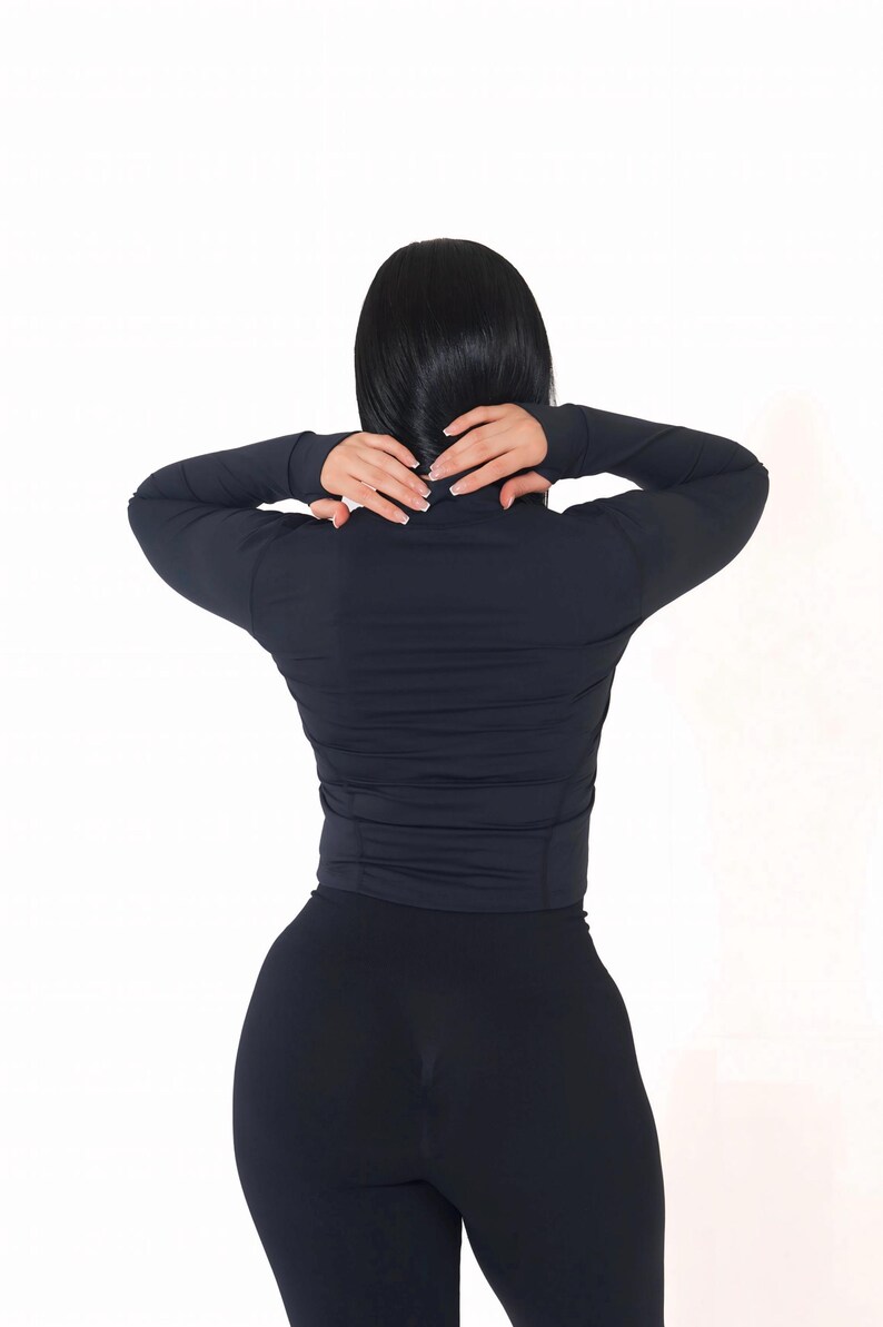 May include: A black long-sleeved shirt with a mock neck and a zipper. The shirt is made of a stretchy fabric and has a fitted silhouette.