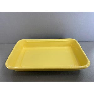 May include: A rectangular, bright yellow ceramic baking dish. The dish has slightly rounded corners and a raised rim. The interior is smooth and glossy. The dish is designed for baking and serving.