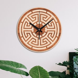 May include: A wooden wall clock with a brown and white geometric design. The clock face features a circular pattern of interlocking lines, resembling a maze or labyrinth. The clock hands are black.