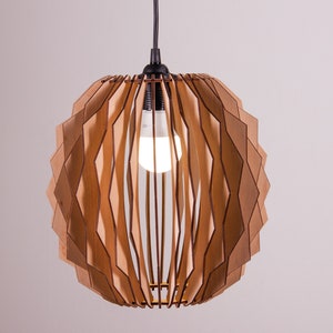 Può includere: Una lampada a sospensione in legno con un design geometrico. La lampada è realizzata con pezzi di legno stratificati in tonalità marroni e beige, creando un motivo unico e traforato. All'interno è visibile una lampadina.