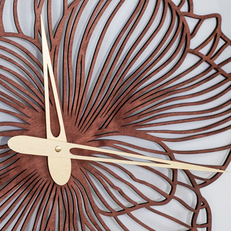 May include: A brown wooden clock with a gold-colored clock hand and a decorative design of a flower with intricate details.