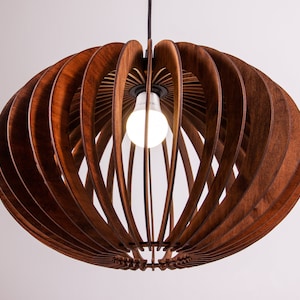 Può includere: Un lampadario a sospensione in legno marrone con forma sferica e una lampadina all'interno. Il lampadario è realizzato con sottili lamelle di legno curve che creano un motivo geometrico.