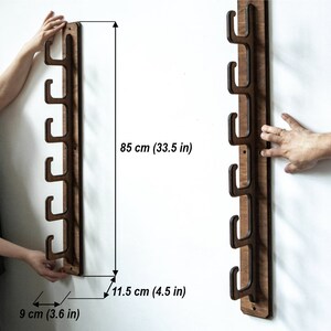 May include: A wooden wall-mounted rack with five hooks for hanging items. The rack is 33.5 inches tall and 4.5 inches wide.