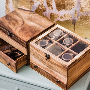 Pu&ograve; includere: Due scatole di legno con un cassetto e un coperchio di vetro. La scatola superiore ha sei scomparti per riporre gli orologi. La scatola inferiore ha un cassetto per riporre altri oggetti.