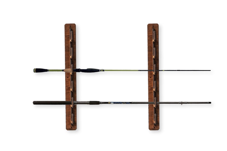 May include: A wooden wall-mounted fishing rod rack with two rows of slots for storing fishing rods. The rack is made of dark brown wood and has a natural wood finish. Two fishing rods are displayed in the rack.