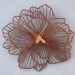 May include: A brown wooden wall clock with a flower design and gold-colored hands.