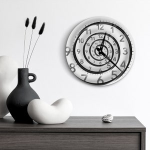 May include: A white clock with black numbers and hands. The numbers are arranged in a spiral pattern, creating a unique and modern design.