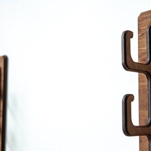 May include: Two wooden wall-mounted hooks with three hooks each. The hooks are made of dark brown wood and have a simple, modern design.