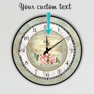 Pu&ograve; includere: Orologio da parete rotondo con un design vintage. Il quadrante presenta uno sfondo azzurro chiaro invecchiato con una composizione floreale centrale di rose rosa. L'orologio ha lancette nere e numeri romani.