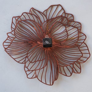 May include: A brown wooden wall clock with a delicate floral design. The clock face is hidden behind the intricate design.