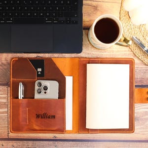 May include: A brown leather portfolio with a notepad, pen, phone, and card slots. The portfolio has the name "William" embossed on the front.