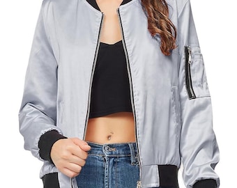 May include: A light grey bomber jacket with black collar, cuffs, and trim. It features a zip closure and a zipped pocket on the left sleeve. The jacket is made of a shiny, satin-like material.