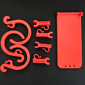 May include: A set of red plastic phone stand parts. The stand includes a back panel, four corner pieces, and two curved pieces that attach to the back panel.