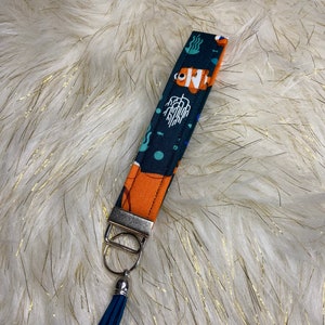May include: A dark blue and orange key chain with a cartoon fish design and a blue tassel.
