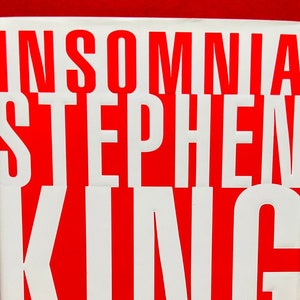 May include: A red hardback book with the title "INSOMNIA" and the author's name "STEPHEN KING" in white letters.