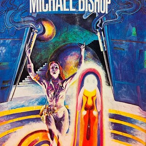 May include: A book cover featuring a colourful illustration of a woman standing in a futuristic setting. The title of the book is "Transfigurations" by Michael Bishop.