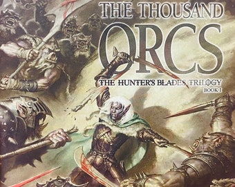 May include: A paperback fantasy novel cover featuring a dark-skinned warrior with a sword fighting a group of orcs. The book title is "The Thousand Orcs" by R.A. Salvatore. The book is part of the "Hunter's Blades Trilogy".