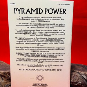 May include: A vintage book cover with a white background and a red and yellow pyramid design. The title is "Pyramid Power" in large, bold, black letters. The book cover also includes the text "...a good environment for transcendental meditation, biofeedback and yoga, in that it surrounds its inhabitants with energy." TIME Magazine. The book is published by Destiny Books, One Park Street, Rochester, Vermont 05767. ISBN 0-89281-106-4.