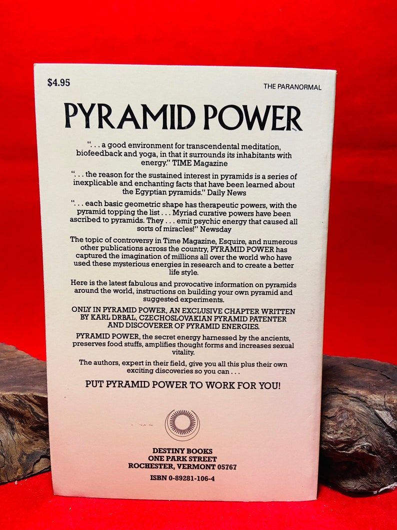 May include: A vintage book cover with a white background and a red and yellow pyramid design. The title is "Pyramid Power" in large, bold, black letters. The book cover also includes the text "...a good environment for transcendental meditation, biofeedback and yoga, in that it surrounds its inhabitants with energy." TIME Magazine. The book is published by Destiny Books, One Park Street, Rochester, Vermont 05767. ISBN 0-89281-106-4.