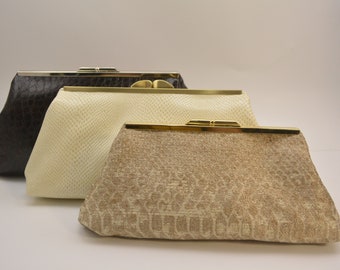 May include: Three different clutch purses, one brown, one cream, and one beige with a patterned design.