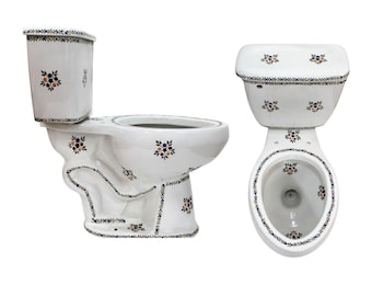 Op de afbeelding: Een wit keramisch toilet getoond vanuit zijaanzicht en bovenaanzicht, voorzien van een decoratief patroon van kleine blauwe, oranje en zwarte bloemmotieven en geometrische randen op het reservoir, de pot en de voet.