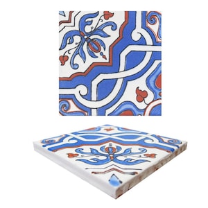 Può includere: Piastrella quadrata in ceramica con un elaborato motivo floreale blu, rosso e bianco. La piastrella presenta un motivo ripetuto di fiori e viti stilizzate. La piastrella è mostrata ad angolo, mostrando il lato e la parte superiore.