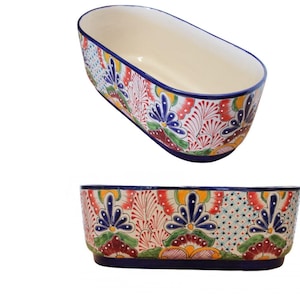 May include: Two oval ceramic planters with a colourful floral design. The planters are white with blue, red, yellow, and green accents. The design features stylised flowers and leaves.