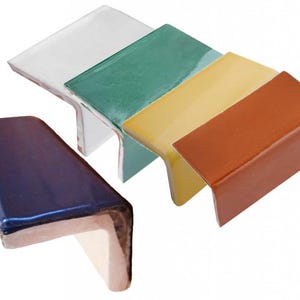 May include: A collection of colorful ceramic corner tiles in various shades. The tiles are in white, green, yellow, brown, and blue. Each tile has a glossy finish and a right-angle shape, suitable for edging or framing.