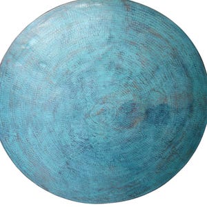 May include: A circular metal plate in a turquoise hue, featuring a textured surface and a concentric circular design. The plate has a distressed finish, giving it a rustic appearance. The plate is isolated on a white background.