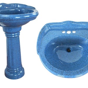 Könnte beinhalten: Ein blaues Standwaschbecken mit gesprenkelter Oberfläche und ein passendes blaues Wandwaschbecken. Das Becken verfügt über einen gewellten Rand, ein zentrales Abflussloch und drei vorgebohrte Armaturenlöcher auf der hinteren Ablagefläche.