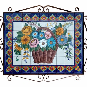May include: A colorful ceramic tile wall hanging with a floral design. The tile is framed with a metal border and features a basket of flowers with a small bird.