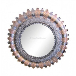 May include: A round mirror with a decorative metal frame. The frame is made of silver and copper metal and features a design of overlapping feathers. The mirror is surrounded by a beaded border.