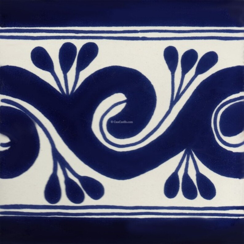 May include: Square ceramic tile with a white background and a repeating blue floral design. The design features a stylized wave pattern with teardrop-shaped elements and thin lines. The tile has a border of blue and white lines.