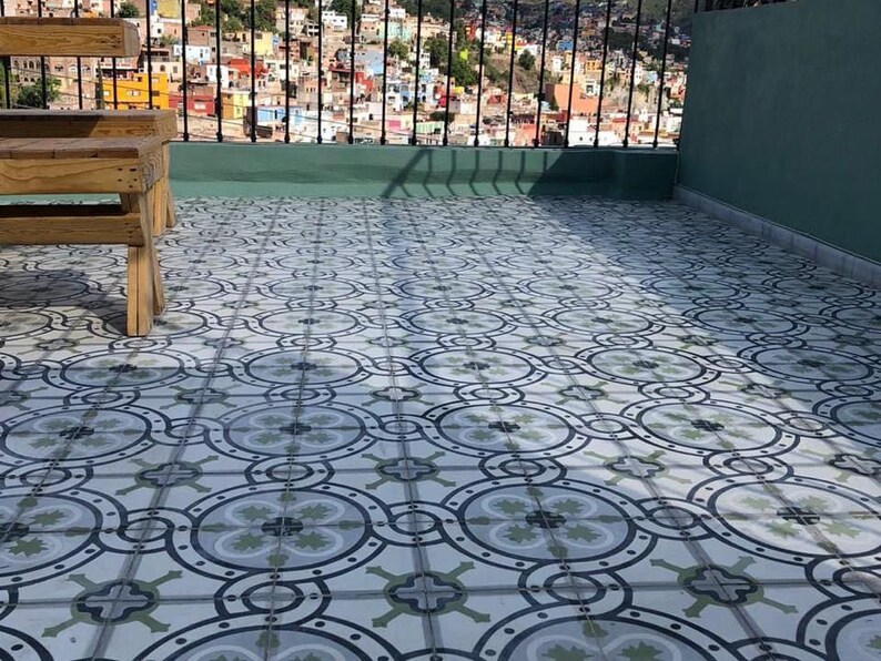 May include: A rooftop patio with a patterned tile floor. Two wooden benches are on the patio, with a view of a city in the background.