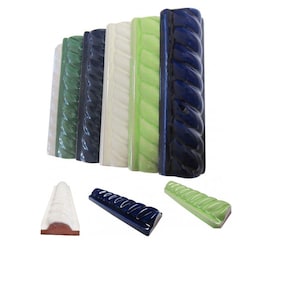 Op de afbeelding: Een verzameling keramische tegels in verschillende kleuren, waaronder wit, groen, marineblauw en blauw. Elke tegel heeft een textuur, touwachtig ontwerp. De tegels zijn verticaal en horizontaal gerangschikt, wat hun decoratieve potentieel aantoont.