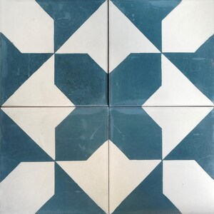 Puede incluir: Cuatro baldosas cuadradas dispuestas juntas, cada una con un patrón geométrico. El diseño presenta formas blancas y azul verdoso, creando un motivo en forma de estrella. Las baldosas tienen un acabado brillante, adecuado para suelos o decoración de paredes.