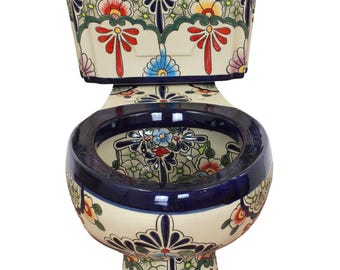 Op de afbeelding: Een keramisch toilet met een crèmekleurige basis versierd met handgeschilderde bloemmotieven en geometrische patronen in blauw, rood, geel en groen. Het toilet is voorzien van een bijpassend reservoir, een donkerblauwe zitting en een donkerblauwe rand.