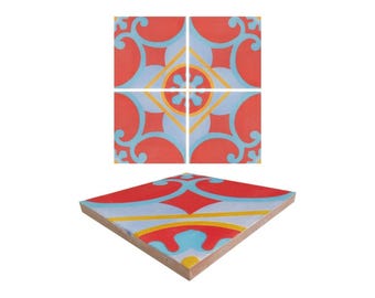 May include: Four red, blue, and yellow patterned ceramic tiles arranged in a square. The tiles have a geometric design with a central flower motif.