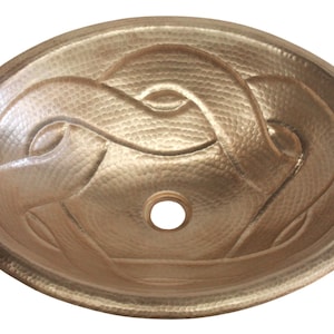 May include: Oval copper sink with an intricate, raised design. The hammered metal basin features a central drain hole and a decorative pattern of interwoven lines. The sink has a warm, metallic finish.
