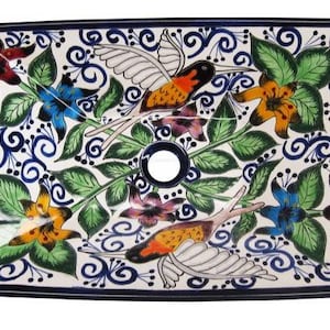 May include: A white ceramic rectangular sink with a blue rim and a colorful floral and hummingbird design. The sink has a drain hole in the center.