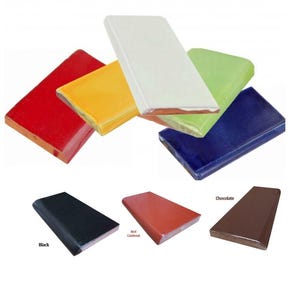 Op de afbeelding: Rechthoekige keramische tegels in diverse kleuren, waaronder rood, geel, wit, groen en blauw. Extra tegels in zwart, rood en chocolade zijn ook te zien. De tegels hebben een glanzende afwerking en zijn waarschijnlijk voor interieur of constructie.