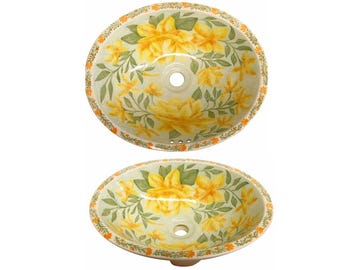 May include: Oval ceramic sink with a floral design featuring yellow flowers and green leaves on a light green background. The sink has a white rim with a decorative orange and green border.