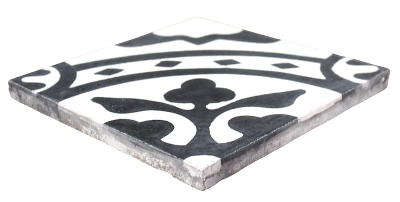 May include: Black and white ceramic tile with a geometric pattern. The tile has a distressed look and features a floral design.