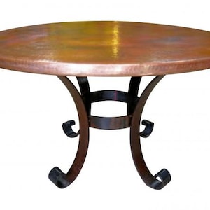 May include: A round copper-topped table with a dark brown, wrought iron base. The table has a warm, metallic finish and a decorative, curved leg design. The table is suitable for indoor use.
