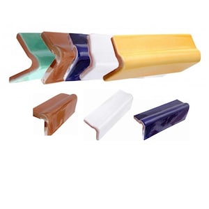 Könnte beinhalten: Sortiment an Keramik-Eckfliesen in verschiedenen Farben, darunter Grün, Braun, Blau, Weiß und Gelb. Die Fliesen sind rechtwinklig geformt und haben eine glatte, glasierte Oberfläche.