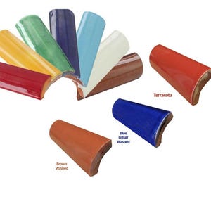 Op de afbeelding: Assortiment van keramische tegelranden in verschillende kleuren, waaronder terracotta, blauw kobalt gewassen en bruin gewassen. De tegels zijn gebogen en hebben een glanzende afwerking.