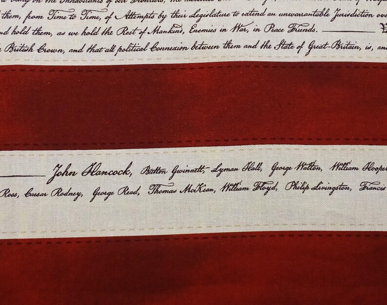 May include: Close-up of a fabric with a red and cream color scheme. The fabric features text from the Declaration of Independence, including the names of signers like John Hancock. The design resembles a flag.