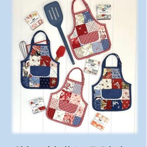 May include: Image of four patchwork apron-shaped hot pads in red, white, and blue patterns. The text "Apron Hot Pads" is at the top. The hot pads are approximately 9 inches high and 8 inches wide. A blue spatula and red spatula are also in the image.