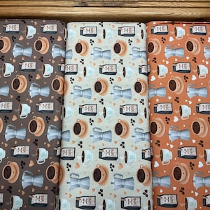 May include: Three fabric swatches with a coffee-themed pattern. The designs feature coffee cups, espresso makers, coffee beans, and coffee pots in shades of brown, beige, and orange. The fabric is likely cotton or a similar material.